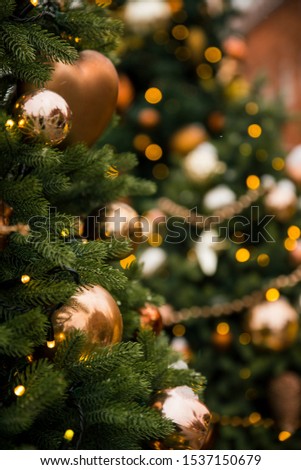 branches of Christmas trees with gold and brown toys, balls, snow and garlands close-up on a blurred background bokeh, winter
