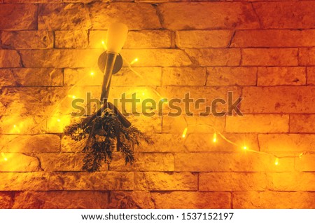 A beautiful Christmas tree branch and lights hanging on a stone wall