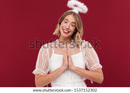 Photo of smiling woman angel in carnival costume isolated over red wall background make pray gesture.