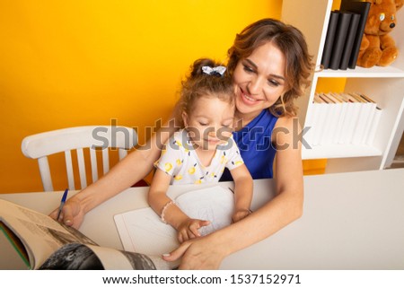Happy kid with mother in a playroom drawing together.