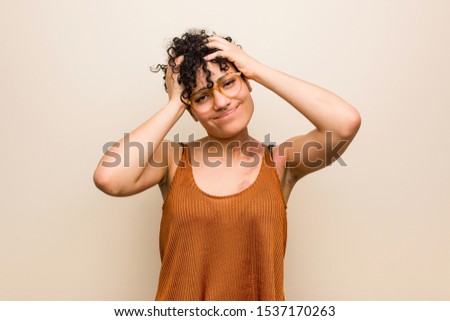 Young african american woman with skin birth mark laughs joyfully keeping hands on head. Happiness concept.