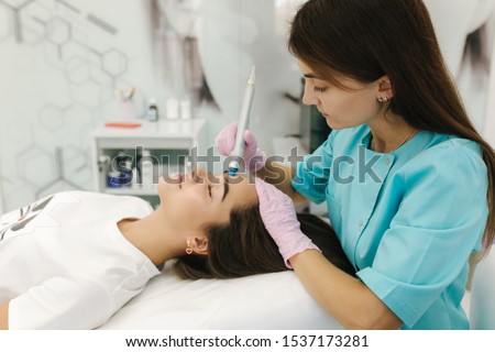 Professional female cosmetologist doing hydrafacial procedure for beautiful girl. Soft skin. Cosmetology clinic Royalty-Free Stock Photo #1537173281