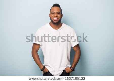 Smiling african American man in casual clothes and glasses isolated on blue studio background look at camera, happy positive biracial male model wear spectacles posing advertise optics salon