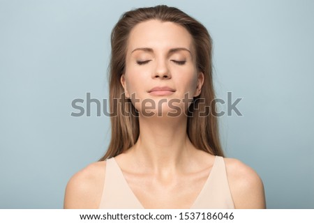 Close up of calm happy Caucasian millennial woman isolated on blue studio background relax with eyes closed meditate relieve negativity, peaceful young female breathe fresh air, stress free concept Royalty-Free Stock Photo #1537186046