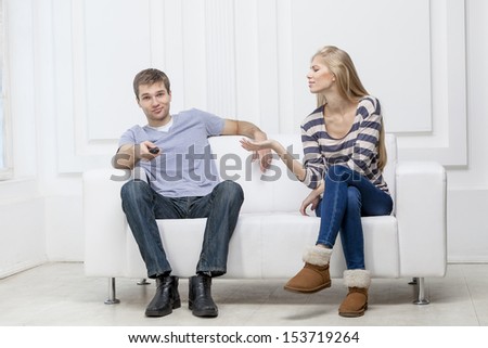 young caucasian couple sitting on couch holding remote control watching tv