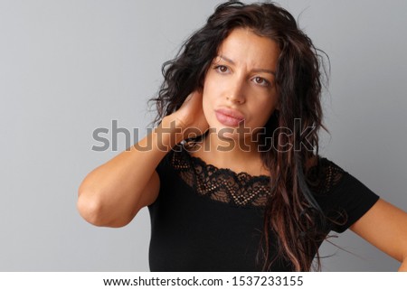 Image of thinking young woman standing over a gray background
