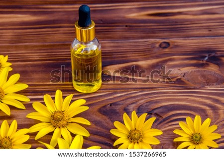 yellow flowers and cosmetic oil in a bottle on wooden background