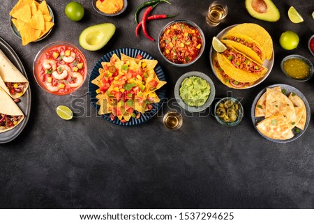Mexican food, many dishes of the cuisine of Mexico, flat lay, shot from the top on a black background with a place for text. Nachos, tequila, guacamole etc