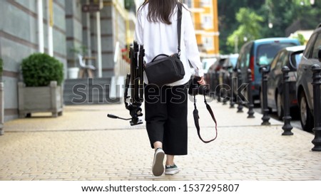 Woman photographer walking on street with equipment, going to work, photoshoot