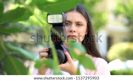Female with camera hiding behind trees, journalist searching for sensation