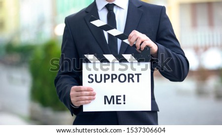 Support me phrase on clapperboard in hands of politician, pre-election campaign