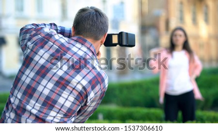 Female model posing to male photographer camera, photo session in summer park