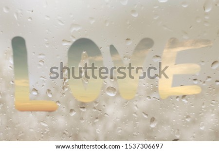 Love heart symbol inscription on wet sweaty glass after rain