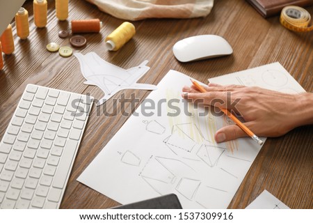 Male fashion designer working at wooden table, closeup