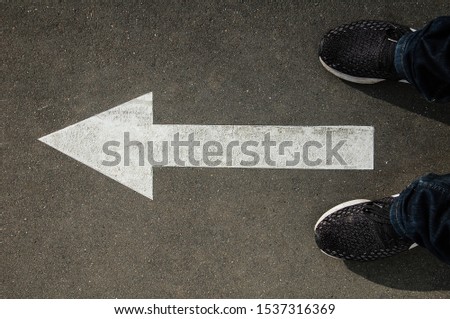 feet in front of a white arrow on the asphalt