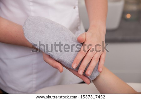 Female hand in beauty spa salon with paraffin wax in glove. Manicure and skincare concept. Woman beauty cosmetology routine bright scene Royalty-Free Stock Photo #1537317452