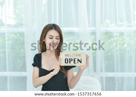 Beautiful Asian woman holding a sign to open a shop And welcome