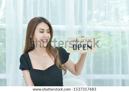 Beautiful Asian woman holding a sign to open a shop And welcome