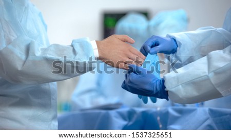 Assistant wearing main surgeon gloves, before operation in sterile hospital room