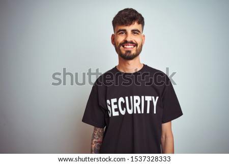 Young safeguard man with tattoo wering security uniform over isolated white background with a happy and cool smile on face. Lucky person.