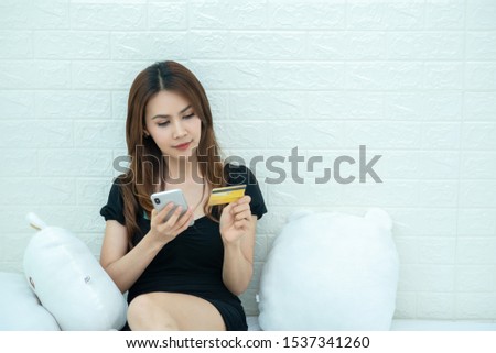Model girl sitting and watching phone and credit card