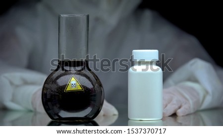 Poisonous liquid and jar antidote pills standing on table, scientific experiment