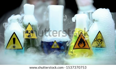 Marked dangerous liquids evaporating in flasks in front laboratory worker