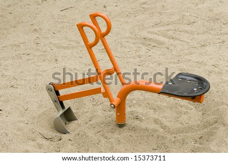 A close up of an orange and silver toy bulldozer in a sandbox.