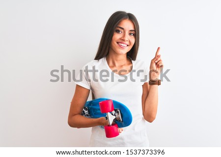 Young beautiful woman holding skate standing over isolated white background very happy pointing with hand and finger to the side