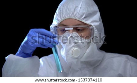 Toxic laboratory worker studying blue fluid in test tube harmful work conditions