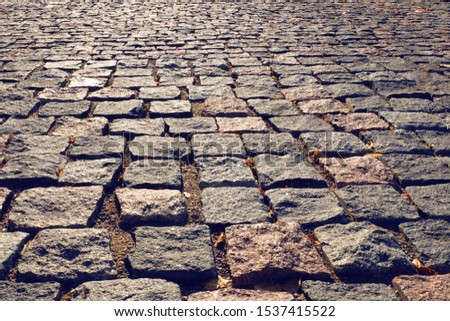 Stone road close up. Old pavement of granite. Brown square cobblestone sidewalk. Mock up or vintage grunge texture.
