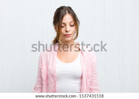 young pretty woman wondering, thinking happy thoughts and ideas, daydreaming, looking to copy space on side against wooden white wood wall