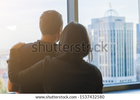 Silhouettes of two couples hugging and looking out the window. Back view.