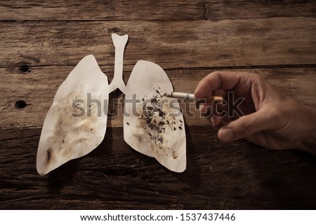 Advertising style picture of Tobacco and lung cancer, Medical warning, stop smoking and smoking kills campaign. conceptual image of hand with burning cigarette using lungs as ashtray.