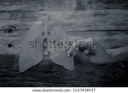 Advertising style picture of Tobacco and lung cancer, Medical warning, stop smoking and smoking kills campaign. Conceptual image of hand with burning cigarette using lungs as ashtray.