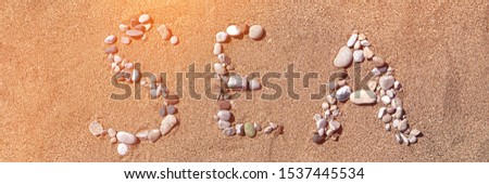 The word SEA created with color sea pebbles the sand.