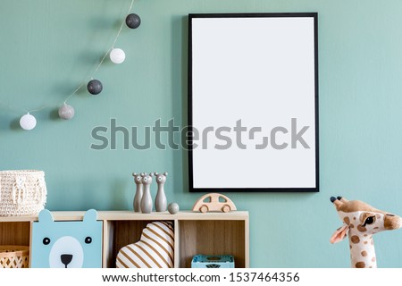 Stylish scandinavian newborn baby room with wooden cabinet, toys, mock up poster frame and children's accessories. Modern interior with eucalyptus background wall and cottona balls. Modern home decor.