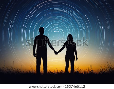 Silhouette of young couple under stars. The concept on the theme of love, earth day holiday. Elements of this image furnished by NASA.

