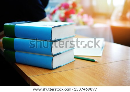 Pile of hardcover books on study desk in a library or in a study room, selective focused picture of books on a desk and a pencil. Educational or academic concept image related to literature & history