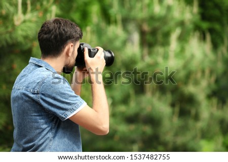Photographer taking photo with professional camera in park. Space for text