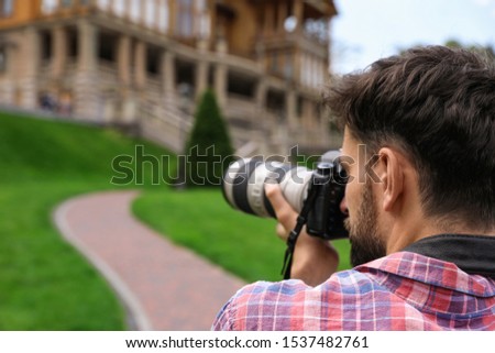 Photographer taking photo of beautiful house with professional camera outdoors