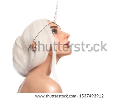 Beautiful woman unicorn closeup stylish makeup with glitter posing on isolated white background. Halloween look concept. Beautiful girl with unicorn horn. copy space