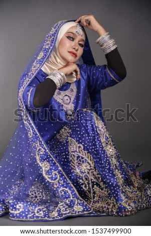 Beautiful hijab girl wearing traditional India costume blue lehenga choli or saree with kundan jewelry set isolated over grey background. Happy Deepavali celebration and Bollywood concept.