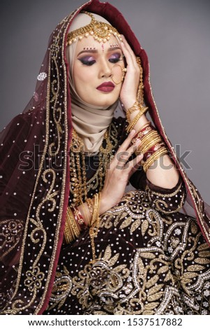 Beautiful hijab girl wearing traditional India costume lehenga choli or saree with kundan jewelry set isolated over grey background. Happy Deepavali celebration and Bollywood concept.