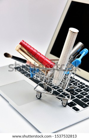 Woman's items and cosmetics in shopping cart, Woman's hands using mobile phone, money, laptop and credit card, Beauty online shopping concept