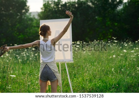 young beautiful woman looking at the camera stylish model outdoors easel