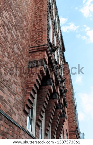 A vertical low angle shot of a red building under the beautiful cloudy sky