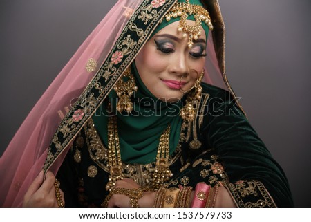 Beautiful hijab girl wearing traditional India costume lehenga choli or saree with kundan jewelry set isolated over grey background. Deepavali celebration and Bollywood concept