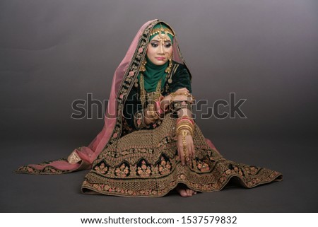 Beautiful hijab girl wearing traditional India costume lehenga choli or saree with kundan jewelry set isolated over grey background. Deepavali celebration and Bollywood concept