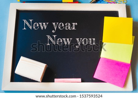New year new you concept, Wood chalk board and colorful paper with pen, pencil and clips in light blue background
